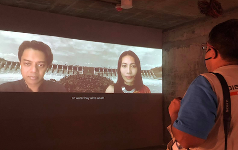 Photo of video installation with faces of Naeem Mohaiemen and Samari Chakma on the screen