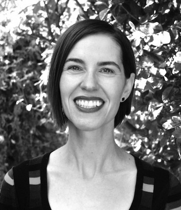 Black and white head shot of Julia Bryan Wilson wearing a striped shirt standing in front of a tree.