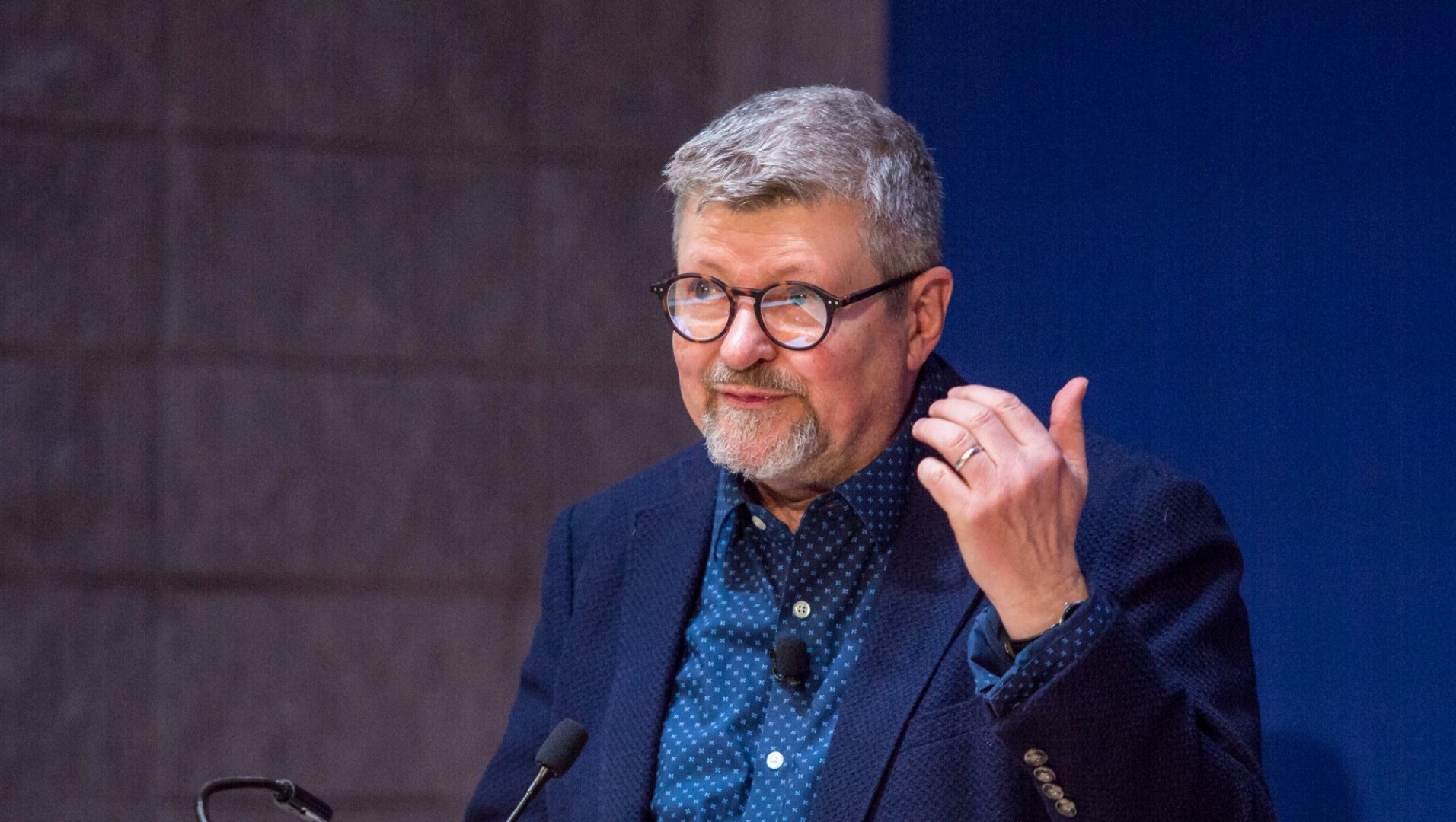 Photo of George Chauncey giving lecture, wearing glasses and blue shirt and jacket