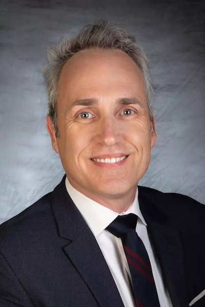 Head shot of Walter Bockting wearing blue suit and navy striped tie