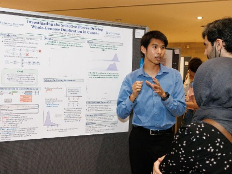 Andrew Chan stands talking to two students in front of his poster