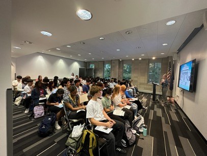 Speaker in front of a screen with a room full of seated students
