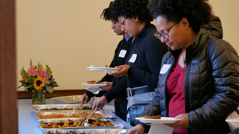 Photo of three women standing in front of trays of food