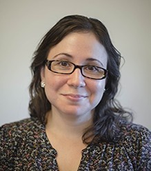 Photo of Angela Garcia with shoulder length brown hair, brown glasses, and a brown shirt 