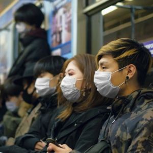 crowded subway with four people in masks side-by-side