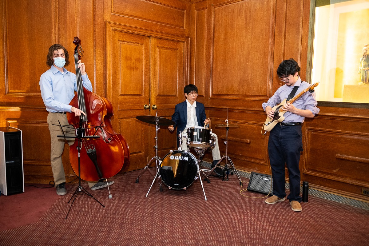 Man playing standup bass, man playing drums, man playing guitar