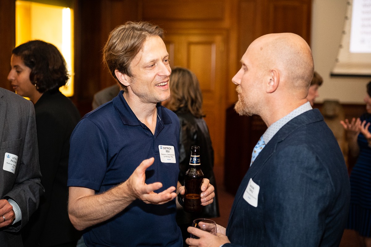 From left to right: Dietrich Egli, Assistant Professor of Developmental Cell Biology (in Pediatrics), spoke with Maxim Topaz, who is Elizabeth Standish Gill Associate Professor of Nursing. Both were awarded tenure in 2022. two men holding drinks and speaking