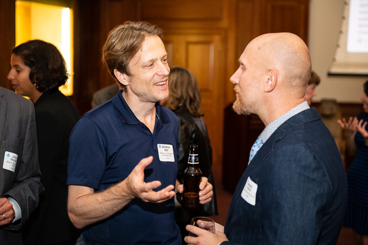 two men holding drinks and speaking