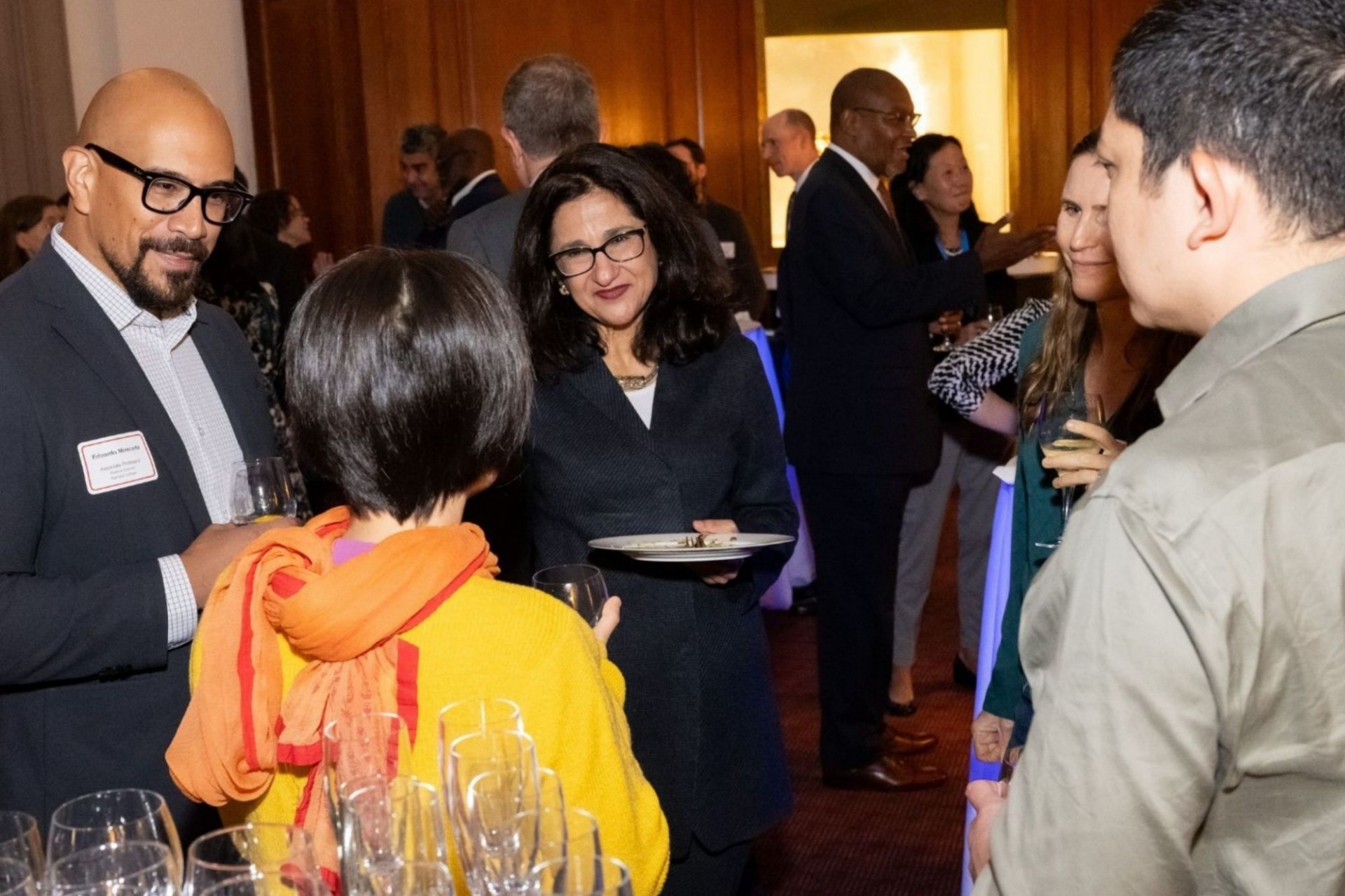 Columbia President Minouche Shafik stands in a group of young, newly tenured faculty at a reception honoring faculty. 