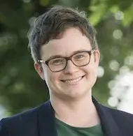 Headshot of Sarah Jubinski with short hair in glasses, blue blazer, and green shirt.