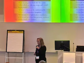 Presenter giving talk in front of powerpoint presentation