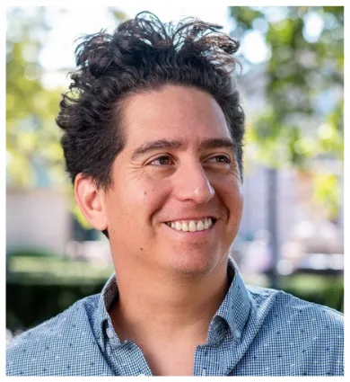 Head shot of Daniel Alarcon looking off to the right. He is wearing a blue shirt.