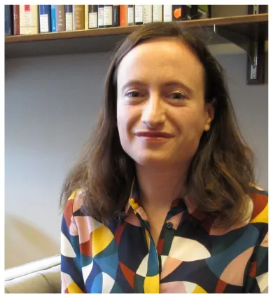 Head shot of Eliza Zingesser in front of bookcase wearing geometric shirt