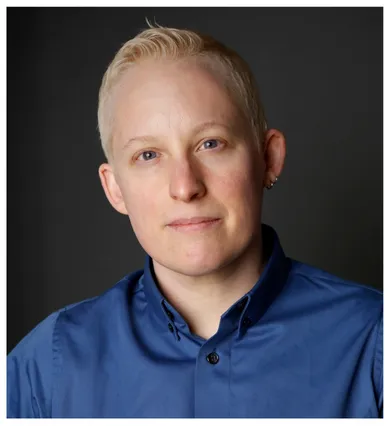 Head shot of Tey Meadow with short blonde hair and a blue button down shirt