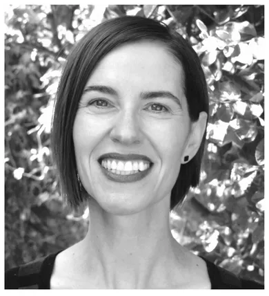 Head shot of Julia Bryan Wilson in black and white, smiling and standing in front of a tree
