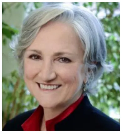 Head shot of Tonda Hughes with gray chin-length hair and a red shirt under a black jacket