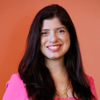 Woman in pink dress smiling with orange background