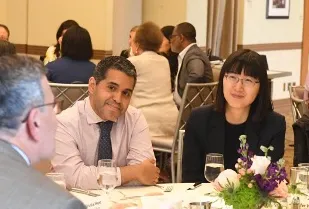 Faculty Billy Caceres and Wei Cai smiling sitting at table