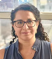 Headshot of Dima Amso, with curly, long dark hair, navy shirt, and glasses