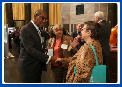 photo o fthree people talking; two are shaking hands