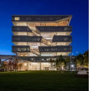 Modern, five-story glass building against a dusk sky