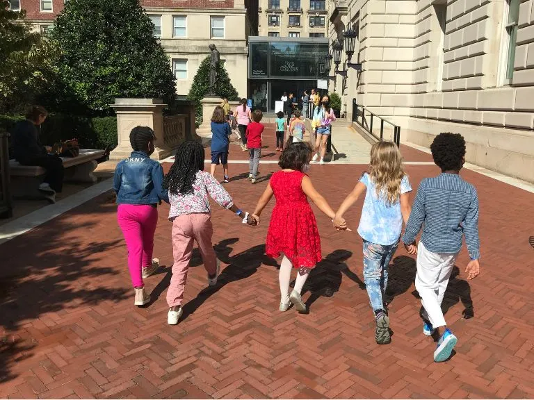 Children walking across campus holding hands